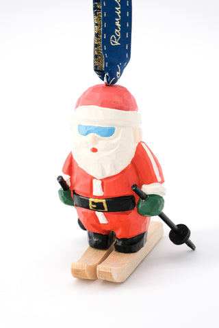 Hand-carved ski Santa ornament with red suit, green gloves, black boots, wooden base