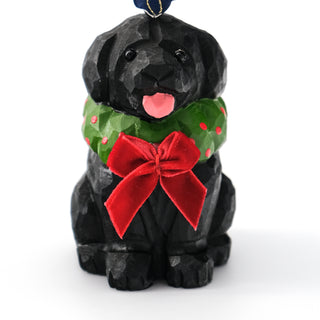 Close-up of black carved dog ornament with green scarf and red velvet bow