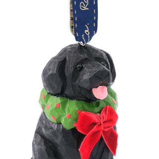 Close-up of black dog ornament wearing green scarf with red bow, hanging ribbon