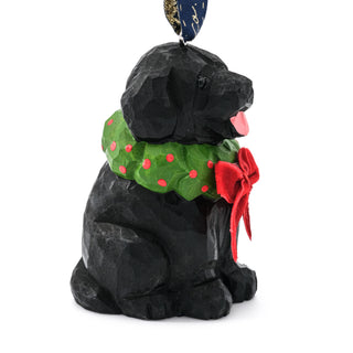 Small black dog ornament with green polka-dot scarf and red bow, side view
