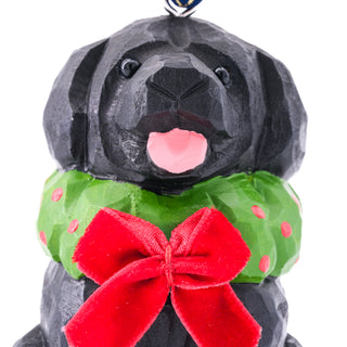 Front close-up of black dog ornament face with green scarf and large red bow