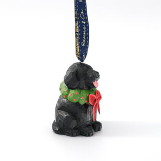 Side view of black dog ornament with green scarf, red bow, and hanging tag