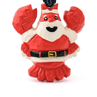 Close-up of hand-carved Santa ornament with red hat, black belt buckle, navy ribbon
