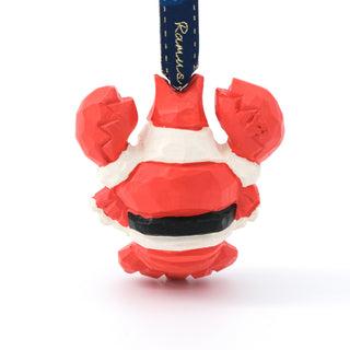 Hand-carved Santa ornament close-up from front with navy ribbon and red outfit