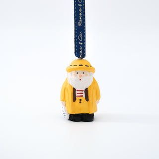 Hand-carved Santa fisherman ornament hanging from a navy ribbon.