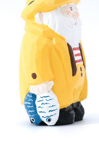 Hand-carved Santa fisherman ornament side view with yellow coat and blue fish base.