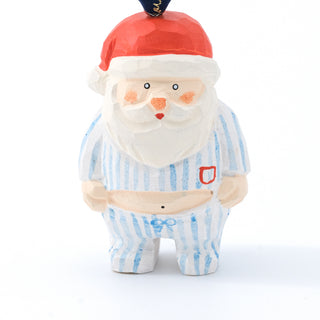 Carved Santa figurine with red cap, white beard, and blue striped pajamas; standing.