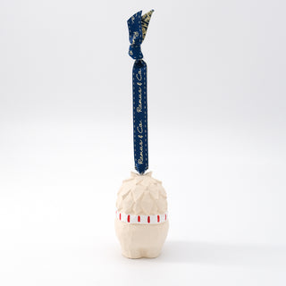 Standing carved yeti ornament with blue hanging ribbon and red striped shirt